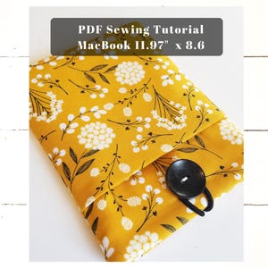 May include: A yellow fabric laptop sleeve with a white floral pattern and a black button closure. The sleeve is designed for a 11.97" x 8.6" MacBook. PDF Sewing Tutorial.