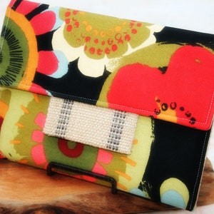 May include: A black fabric clutch with a colorful floral pattern. The clutch has a flap closure and a brown fabric lining.