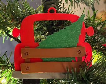 Piccolo camion rosso che trasporta un addobbo per l'albero di Natale