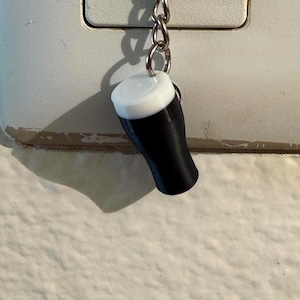 Pu&ograve; includere: Un portachiavi in miniatura a forma di pinta di birra nera con schiuma bianca. Il piccolo ciondolo a forma di bicchiere di birra &egrave; sospeso a una catena argentata.