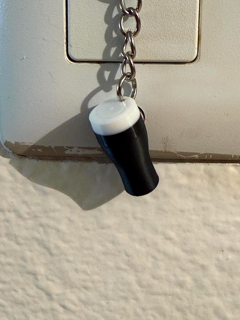 Pu&ograve; includere: Un portachiavi in miniatura a forma di pinta di birra nera con schiuma bianca. Il piccolo ciondolo a forma di bicchiere di birra &egrave; sospeso a una catena argentata.