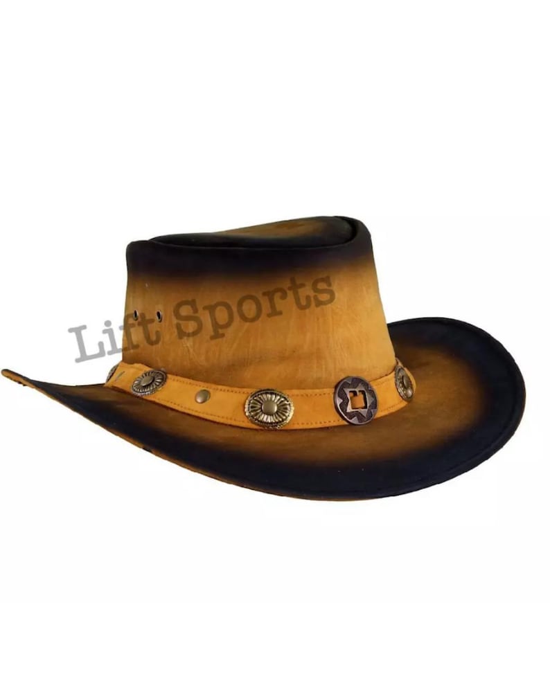 May include: A brown leather cowboy hat with a black brim and decorative metal accents. The hat has a faded, distressed look.