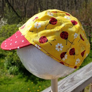 Reversible cotton cap with lady bugs on yellow and red with white polka dots