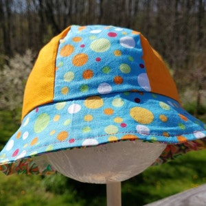 Reversible cotton bucket hat with stars and polka dots in bright greens, pinks, and oranges