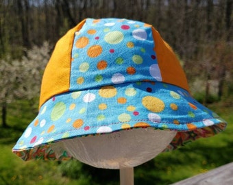 Reversible cotton bucket hat with stars and polka dots in bright greens, pinks, and oranges