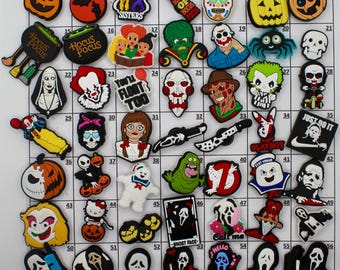 May include: A collection of colorful shoe charms featuring various Halloween and horror-themed characters and symbols. Includes images of skulls, pumpkins, ghosts, and characters from popular movies like "Hocus Pocus" and "Scream". These charms are designed to be attached to shoes.