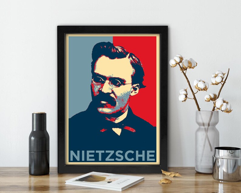 May include: Framed poster featuring a pop art style portrait of Friedrich Nietzsche. The image has a color block design with blue, red, and beige tones. The name "NIETZSCHE" is printed in white at the bottom of the poster.