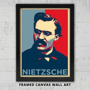 May include: Framed canvas wall art featuring a portrait of Friedrich Nietzsche in a pop art style. The image uses a color palette of red, blue, and beige. The name "NIETZSCHE" is displayed in white block letters at the bottom.