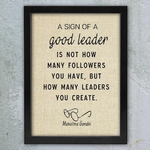 May include: Framed print with the quote "A sign of a good leader is not how many followers you have, but how many leaders you create." The print is in black text on a beige background, with the signature of Mahatma Gandhi.