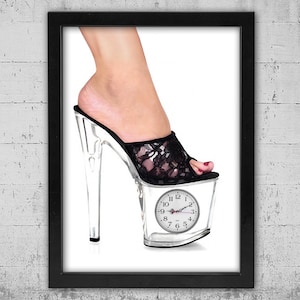May include: A framed print featuring a clear platform high heel shoe with a black lace upper. The platform of the shoe is a clear block containing a clock face. A foot wearing the shoe is visible.