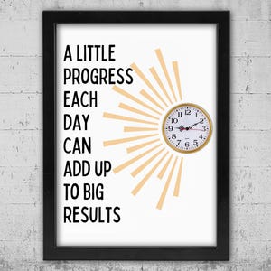 May include: Framed print with the text "A Little Progress Each Day Can Add Up To Big Results." A gold-colored clock is integrated into the design, with sun rays emanating from behind it. The frame is black.