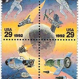 以下が含まれることがあります： 宇宙探査をテーマにしたヴィンテージの米国切手。切手には、宇宙服を着た2人の宇宙飛行士、月、スペースシャトル、衛星が描かれています。切手は1992年のもので、29セントの価値があります。