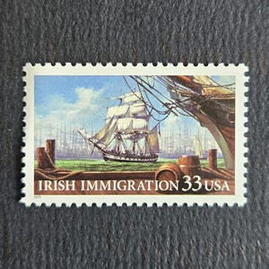 May include: A rectangular postage stamp featuring a sailing ship on the water with wooden barrels in the foreground. The text reads IRISH IMMIGRATION 33 USA and 1999. The stamp has a white serrated border and depicts a maritime scene with rigging.