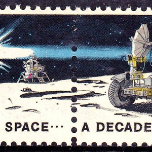 May include: A US postage stamp commemorating a decade of space exploration. The stamp features a black and white illustration of a lunar rover with two astronauts on the moon, a view of Earth in the distance, and the text "UNITED STATES IN SPACE... A DECADE OF ACHIEVEMENT".