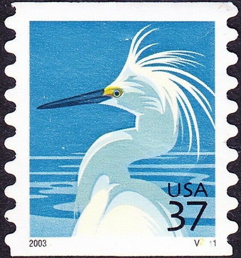 May include: A blue and white postage stamp featuring a white egret with a black beak and yellow eyes. The stamp is from 2003 and has the text "USA 37" printed on it.