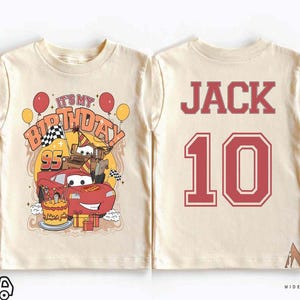 Może przedstawiać: Dwie beżowe koszulki z motywem urodzinowym Cars z przodu i imieniem i numerem z tyłu. Koszulka z przodu ma czerwony samoch&oacute;d wyścigowy, balony i napis "It's My Birthday". Koszulka z tyłu ma imię "Jack" i numer "10" w kolorze czerwonym.