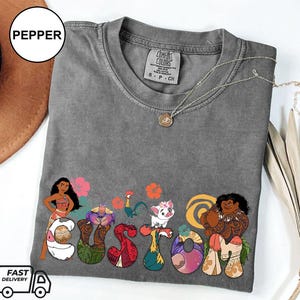 May include: Gray t-shirt with a custom design featuring characters from the animated film Moana. The design includes Moana, Maui, and other characters from the film. The text "CUSTOM" is spelled out using the characters.