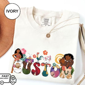 May include: Ivory t-shirt with a custom design featuring characters from the animated film Moana. The design includes Moana, Maui, Pua the pig, Hei Hei the rooster, and a stylized "CUSTOM" text.