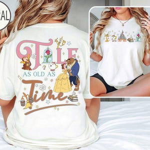 Op de afbeelding: Een wit T-shirt met een grafische print van Belle en het Beest uit de Disney-film Belle en het Beest. De tekst op het shirt luidt "Tale as old as Time".