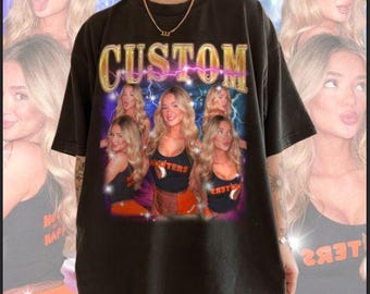 May include: Black oversized t-shirt with a graphic print of women wearing tank tops with the text "CUSTOM" in large gold letters with lightning bolts.