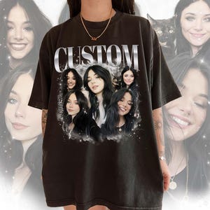 May include: Black t-shirt with a silver "CUSTOM" graphic and a collage of five women's faces. The faces are surrounded by a white cloud-like design.