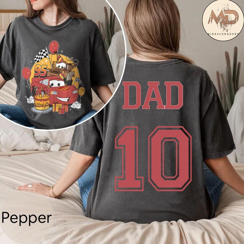 May include: A black t-shirt with the word "DAD" and the number "10" printed on the back in red. The front of the shirt features a cartoon image of Lightning McQueen from the Cars movie celebrating a birthday.