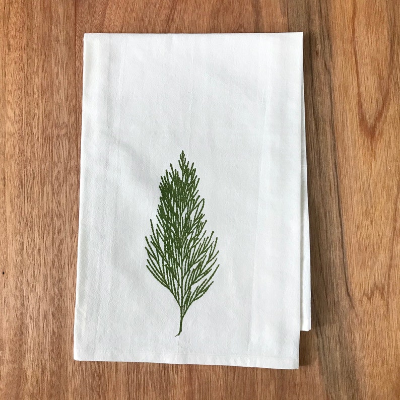 May include: A white kitchen towel with a green stylized image of a pine tree.