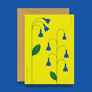 Pode incluir: Um cartão com uma ilustração estilizada de Virginia Bluebells sobre um fundo amarelo brilhante. As flores de campanula são azuis escuras, com caules e folhas verdes. O cartão é acompanhado por um envelope castanho, com o texto "D.C. PLANTS" e "VIRGINIA BLUEBELLS".