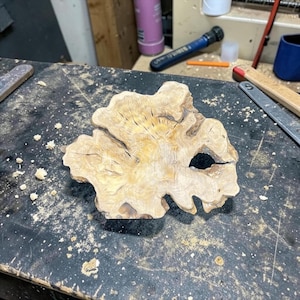 Op de afbeelding: Een lichtgekleurd, onregelmatig gevormd stuk hout met een natuurlijke, organische vorm. Het hout heeft een zichtbare nerf en een gat. Het is waarschijnlijk een decoratief item of een onderdeel voor houtbewerkingsprojecten.