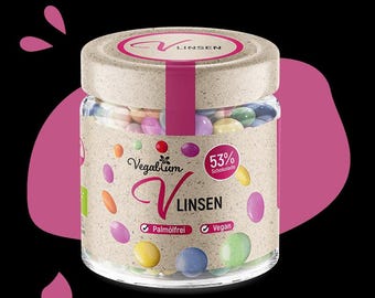 May include: A glass jar filled with colorful chocolate lentils. The jar has a brown paper label with the text "Vegalum V Linsen" and "53% Schokolade". The label also includes the text "Palmfrei" and "Vegan".