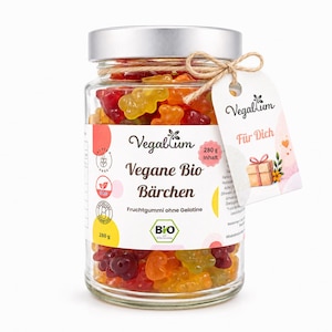 May include: A clear glass jar filled with colorful gummy bears, topped with a silver lid. The label reads Vegablum Vegane Bio Bärchen, 280 g Inhalt, and features a hanging tag with the text Für Dich and a small gift box illustration.