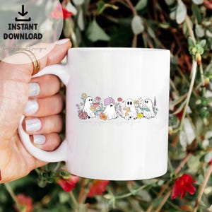 May include: White ceramic mug with a design of four ghosts reading books in a field of flowers. The text "Son Alkon Designs" is at the bottom of the mug.