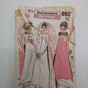 Op de afbeelding: Vintage naaipatroon voor een bruidsjurk en een bruidsmeisjesjurk. Het patroon is van Blackmore le-roy en heeft nummer 892. Het patroon bevat een lange witte bruidsjurk met een sluier, een lange roze bruidsmeisjesjurk en een apart patroon voor een rok.