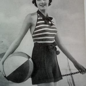 May include: A black and white striped halter top with a bow tie, paired with black shorts. The model is holding a beach ball.