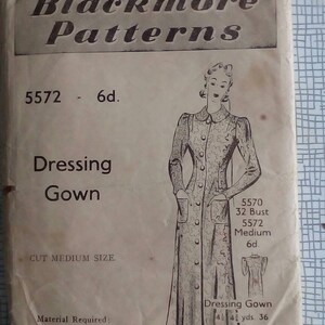 Op de afbeelding: Vintage Blackmore patroon-envelop voor een ochtendjas, met een lijntekening van het kledingstuk. De envelop is bruin met zwarte tekst en illustraties. Inclusief afmetingen en materiaaleisen.