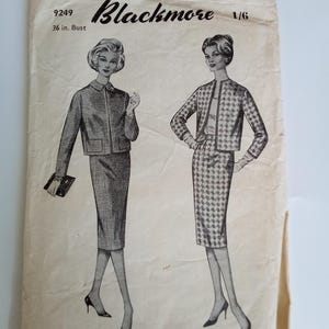 Op de afbeelding: Vintage naaipatroon voor een tweedelig pak met jasje en rok. Het patroon bevat illustraties van het pakontwerp, met de tekst "Blackmore" en "36 in. Bust" zichtbaar. Het patroon is gedrukt op verouderd papier.