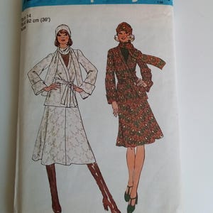 Puede incluir: Patrón de costura Simplicity número 7222 para una falda y una chaqueta. El patrón es para las tallas 14 y un contorno de pecho de 92 cm (36 pulgadas). El patrón muestra a dos mujeres usando la falda y la chaqueta. Una mujer lleva una falda y una chaqueta blancas con un cinturón marrón. La otra mujer lleva una falda y una chaqueta verde y marrón con un cinturón marrón.