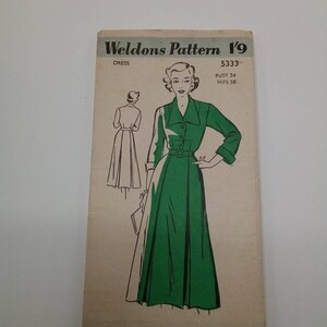 May include: A vintage sewing pattern for a dress, Weldons Pattern 19, size 34 bust and 38 hips. The pattern features a green dress with a collar and a belt.