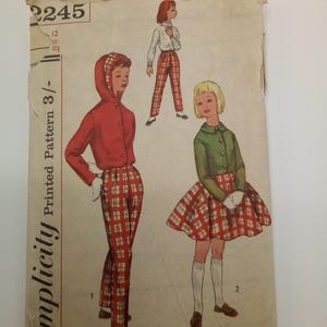 Könnte beinhalten: Simplicity Gedrucktes Schnittmuster 3/-, Größen 12, 30, 32s. Vintage-Schnittmuster für ein Rock- und Hosenset mit Karomuster. Das Schnittmuster beinhaltet eine rote Jacke mit Kapuze, eine grüne Jacke und einen Rock.