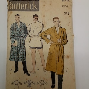 Op de afbeelding: Vintage naaipatroon voor een mannenjas. Het patroon is van Butterick en heeft nummer 8068. Het patroon is voor een kleine maat. Het patroon toont drie verschillende aanzichten van de jas, een in een geruite stof, een in een effen witte stof en een in een effen gele stof.