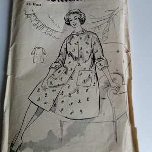Op de afbeelding: Vintage naai-patroon envelop voor een jurk, met een zwart-witte illustratie van een vrouw die een jurk met bloemenprint draagt. Het patroonnummer is 8987 en de maat is 34 bust. De tekst "Blackmore 1/6" staat op de envelop gedrukt.