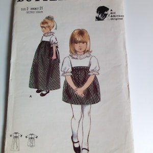 May include: A vintage sewing pattern for a girl's dress, Butterick 3776, size 2, 21 inches chest, 53 cm metric. The pattern includes two styles, a long dress with a plaid skirt and a shorter dress with a plaid skirt. The pattern is by Bill Atkinson.