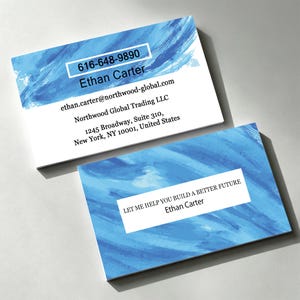 Op de afbeelding: Twee rechthoekige visitekaartjes met een blauw aquarel penseelstreekontwerp. Eén kaart toont de naam Ethan Carter, telefoonnummer 616-648-9890, e-mail en adres. De andere kaart bevat de tekst LET ME HELP YOU BUILD A BETTER FUTURE.