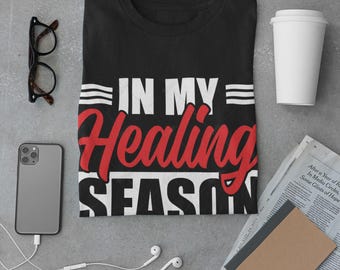 May include: Black t-shirt with white text that reads "In My Healing Season" in red lettering.
