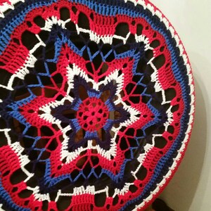 May include: A crocheted red, white, and blue circular cover with a star design in the center.