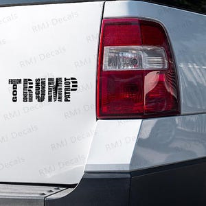 May include: A white SUV with a black decal on the back. The decal says "TRUMP" and is made up of words like "God", "Constitution", "Guns", "Rights", "Military", "Veteran", "Patriot", and "Ammo".