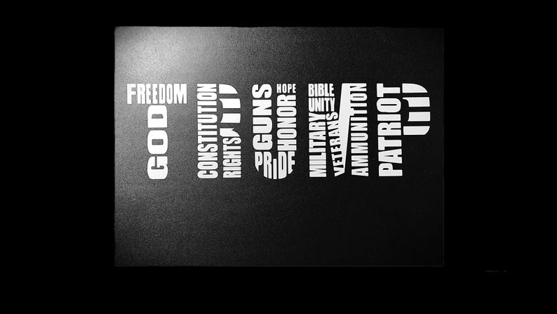 May include: Black and white image with the word "TRUMP" spelled out vertically using words like "God", "Freedom", "Constitution", "Rights", "Guns", "Pride", "Hope", "Honor", "Bible", "Unity", "Military", "Veterans", "Ammunition", and "Patriot".