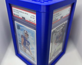 May include: A blue plastic card holder with two graded sports cards inside. The card on the left is a 2018 Panini Donruss Optic Josh Allen card graded EX-MT 9. The card on the right is a 2023 Prizm Dalton Kincaid Silver card.