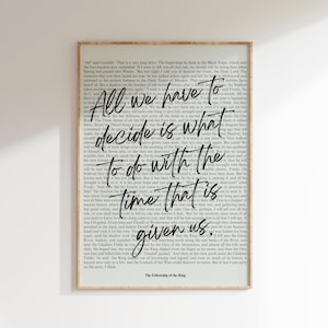 May include: Framed art print featuring a quote from The Lord of the Rings: "All we have to decide is what to do with the time that is given us." The text is in a stylized font over a background of book pages.