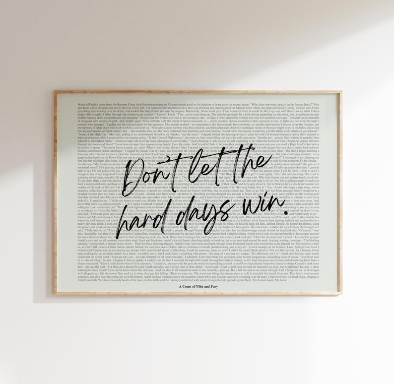 Puede incluir: Una impresi&oacute;n enmarcada con un fondo claro lleno de texto peque&ntilde;o. Las palabras "Don't let the hard days win" est&aacute;n escritas en una fuente cursiva y en negrita en el centro. La parte inferior de la impresi&oacute;n dice "A Court of Mist and Fury".